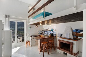 Una cocina con chimenea de ladrillo, barra y vistas a través de un ventanal grande.