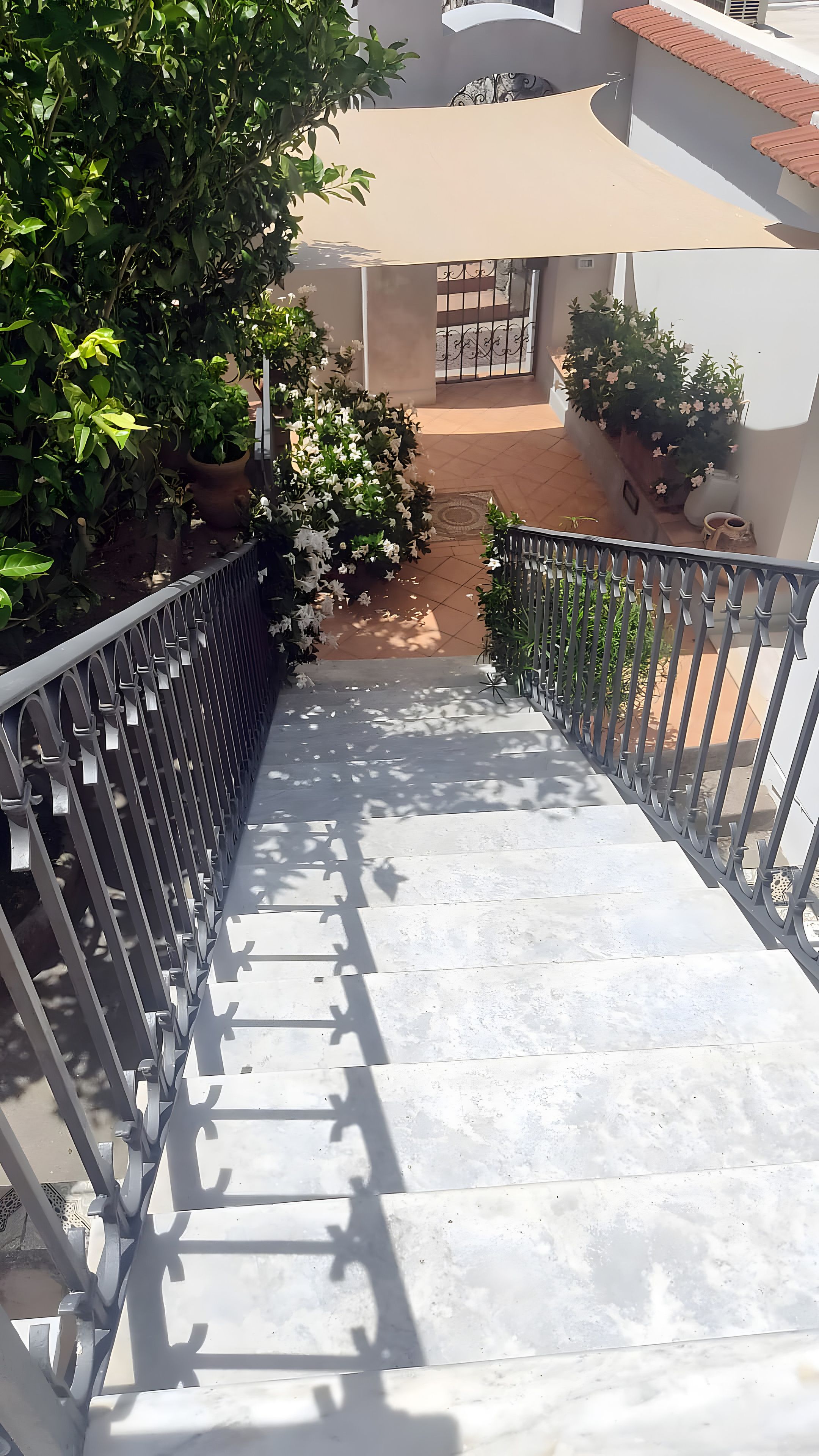 Una escalera de concreto con barandas metálicas que conduce a un acceso con reja.