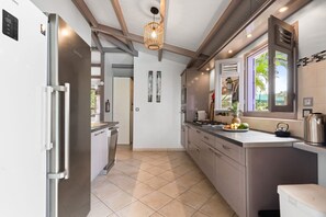A modern kitchen with a stainless steel refrigerator, a built-in oven, and a large window providing natural light. - Villa Atoumo lounge - Four Bedroom Villa, Sleeps 8 (Sainte-Luce)