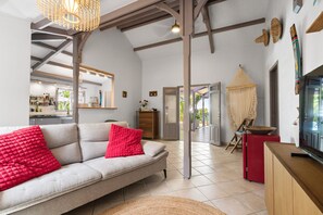 A modern living room with a sofa, a television, and a kitchen in the background. - Villa Atoumo lounge - Four Bedroom Villa, Sleeps 8 (Sainte-Luce)