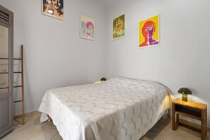 Une chambre à coucher avec un lit, une table de chevet, une lampe et des œuvres d’art murales.
