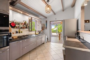 Une cuisine moderne dotée d’un four encastré, d’appareils électroménagers en acier inoxydable et d’une fenêtre donnant sur un jardin.