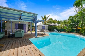 A pool area with a wooden deck, lounge chairs, and a covered patio with a table and chairs. - Villa Atoumo lounge - Four Bedroom Villa, Sleeps 8 (Sainte-Luce)