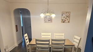 Ein Esszimmer mit Holztisch und Stühlen, einer Kristallleuchter und einer Tür zu einem anderen Raum.
