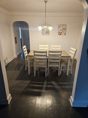 Ein Esszimmer mit Holztisch und Stühlen, einer Kristallleuchter und einer Tür zu einem anderen Raum.