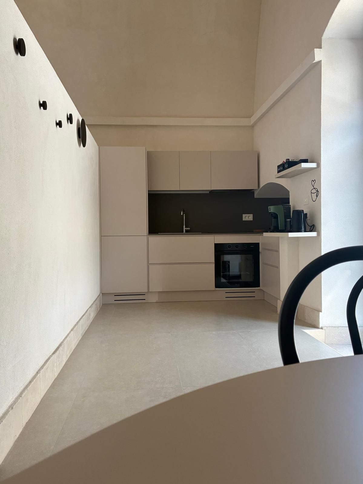 Eine moderne Küche mit weißen Schränken, einer schwarzen Arbeitsplatte und einem eingebauten Backofen.