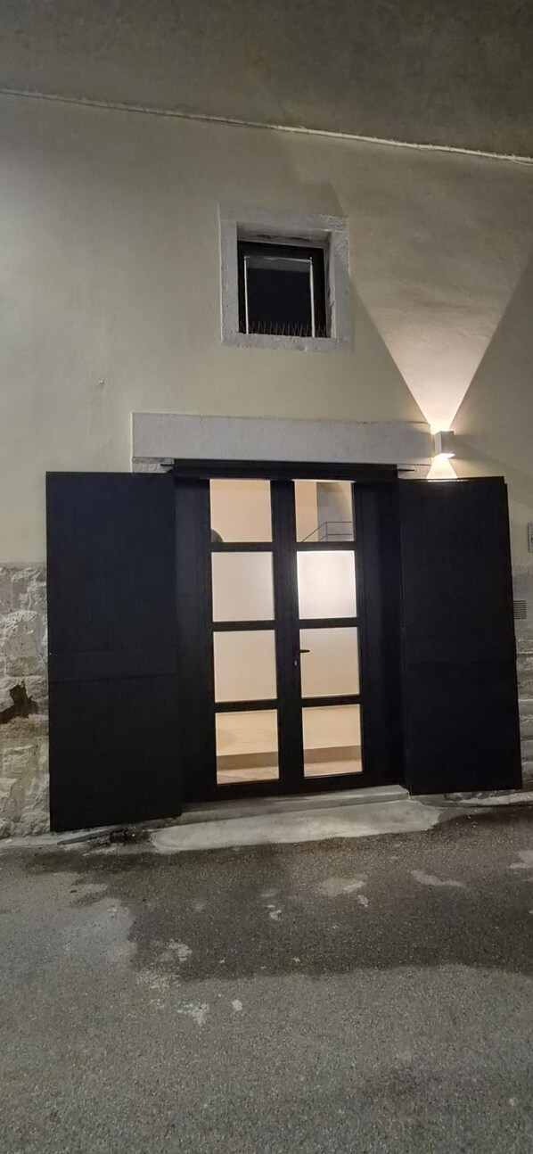 A building entrance with a black gate, a small window above it, and a light source above the window.