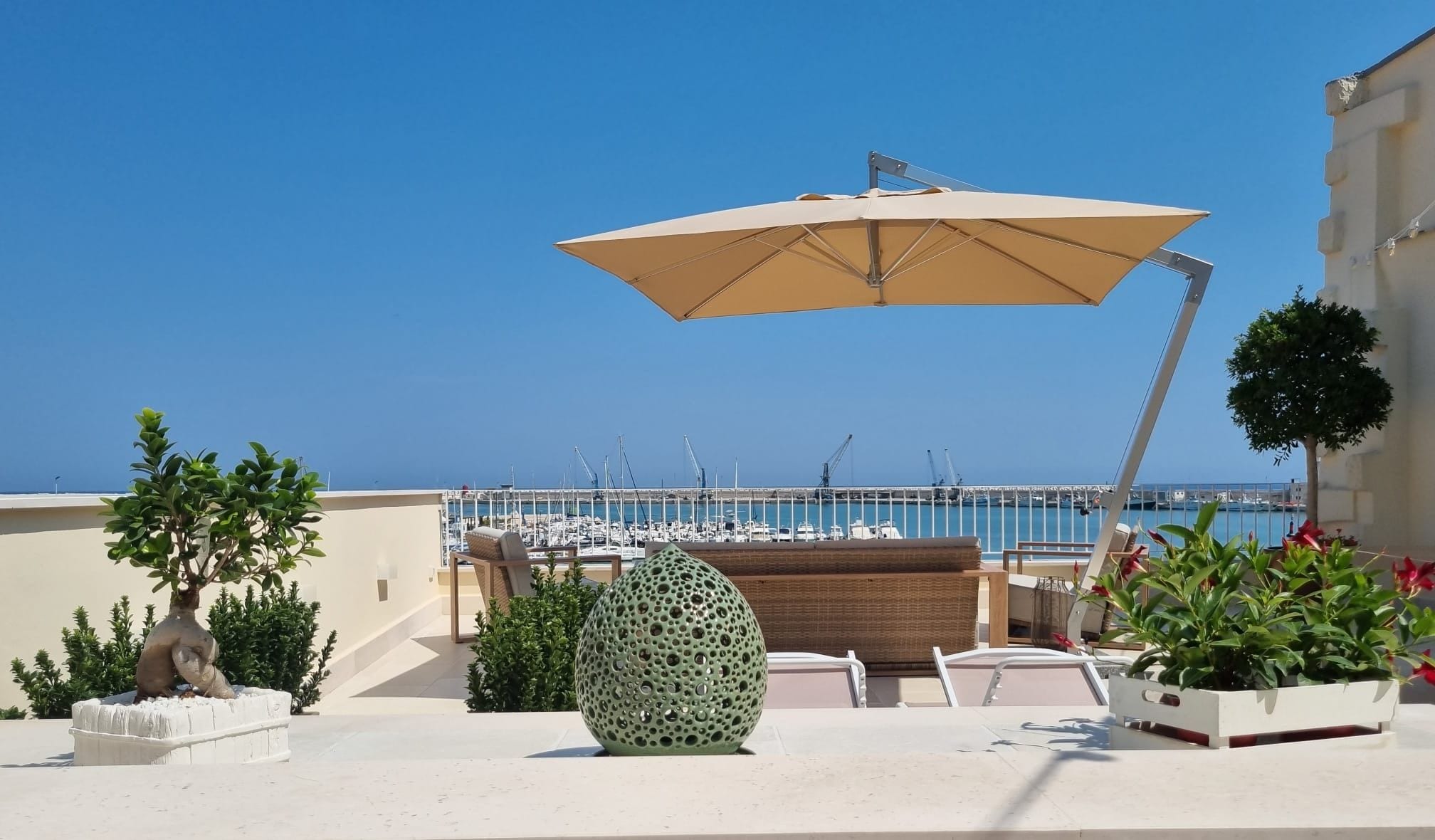 A rooftop terrace with a view of the marina, outdoor seating, and a large umbrella.