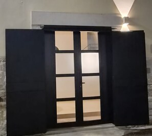 A dark-colored door with a frosted glass panel and a light fixture above it.