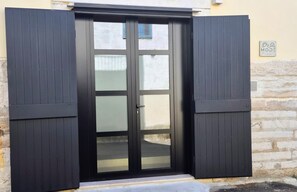 A black door with glass panels and a handle, set in a building with a stone wall and a sign that reads 'MOD'.