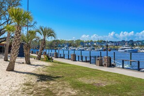 A waterfront promenade with a row of colorful houses, a marina with boats, and palm trees. - Heavenly Sunsets by the beach! (Myrtle Beach)