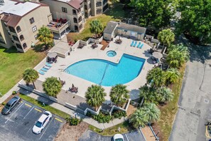 Eine Vogelperspektive auf ein Wohngebiet mit Swimmingpool, Liegestühlen und einem Parkplatz.