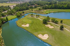 Eine Luftaufnahme eines Golfplatzes mit mehreren Bunkern und einem Teich.