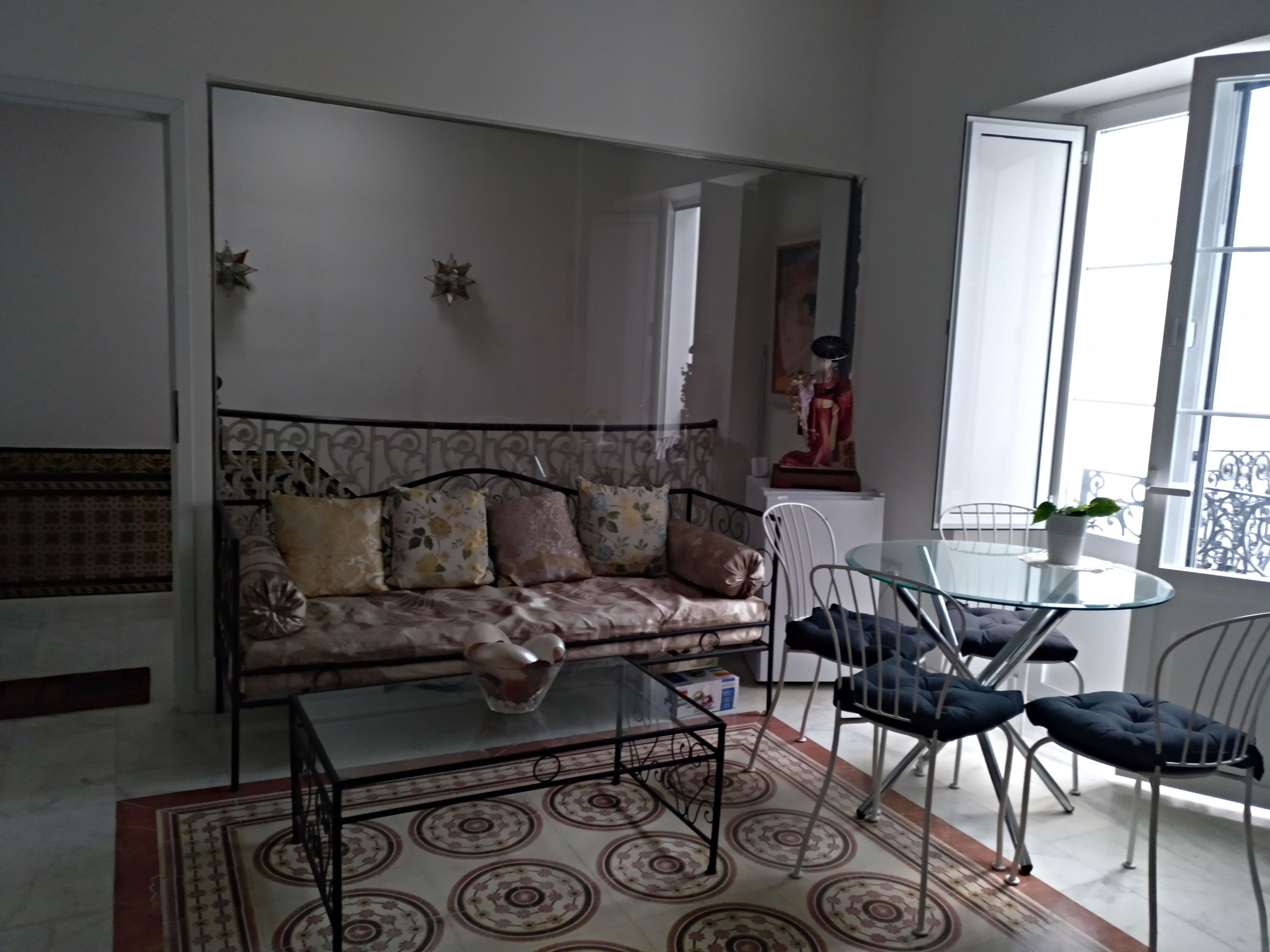 Una sala de estar con un sofá, una mesa de centro de vidrio y una mesa de comedor con sillas.