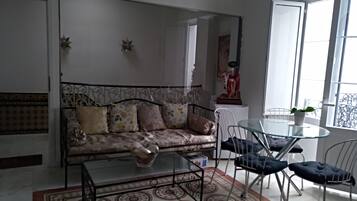 Una sala de estar con un sofá, una mesa de centro de vidrio y una mesa de comedor con sillas.