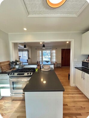 A modern kitchen with a central island, stainless steel appliances, and a view of the outdoors. - Cozy Home with Large Yard (Aurora)