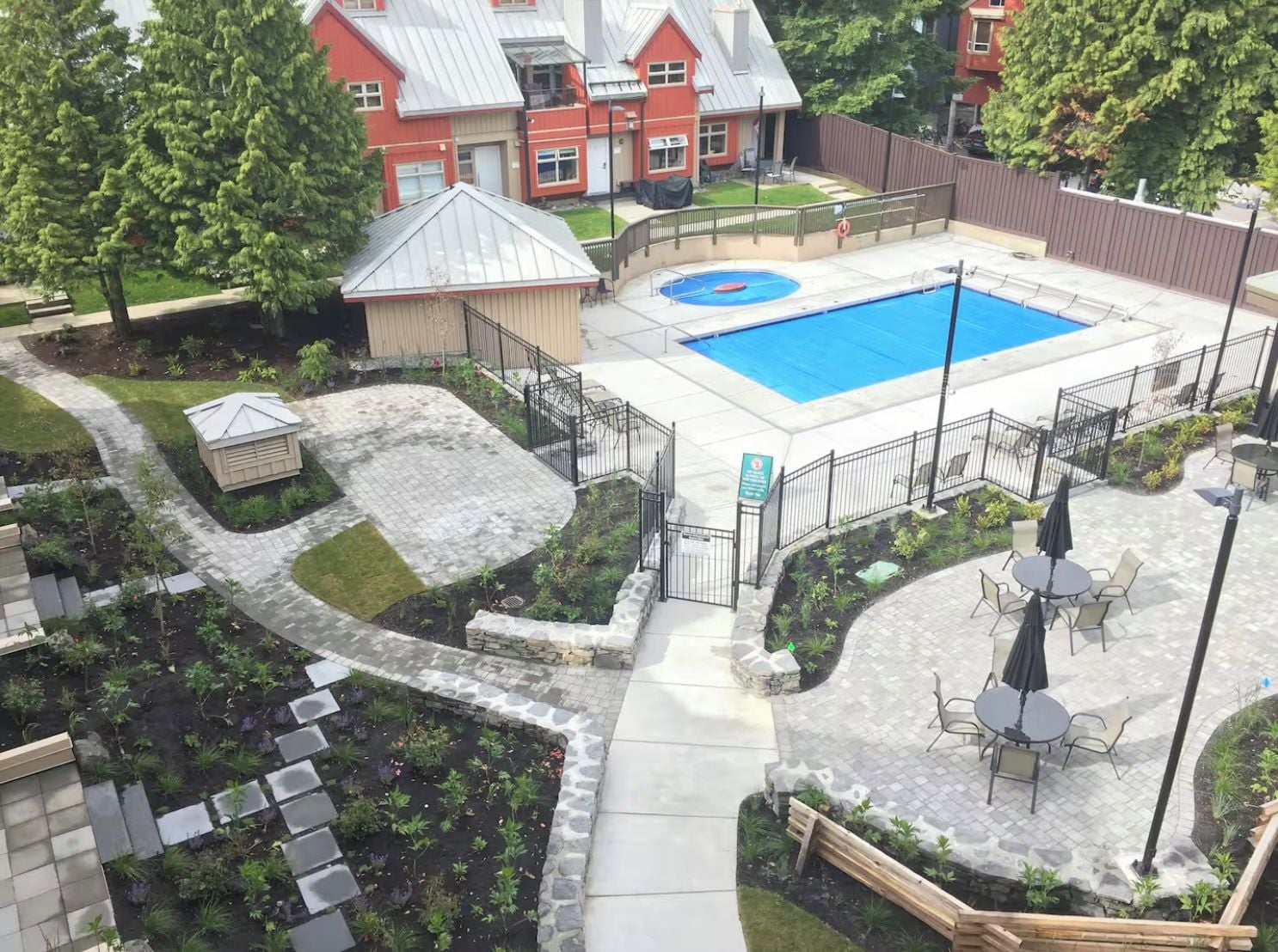 A backyard with a swimming pool, a garden, and a patio area with outdoor furniture.