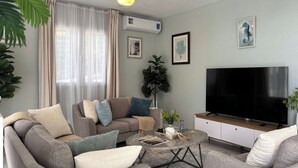 A living room with a sofa set, a coffee table, a TV, and a ceiling fan. - Castaways Haven Apt, Few steps from Mero Beach (Mero)