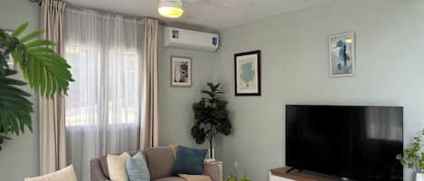 A living room with a sofa, coffee table, TV, and decorative items.