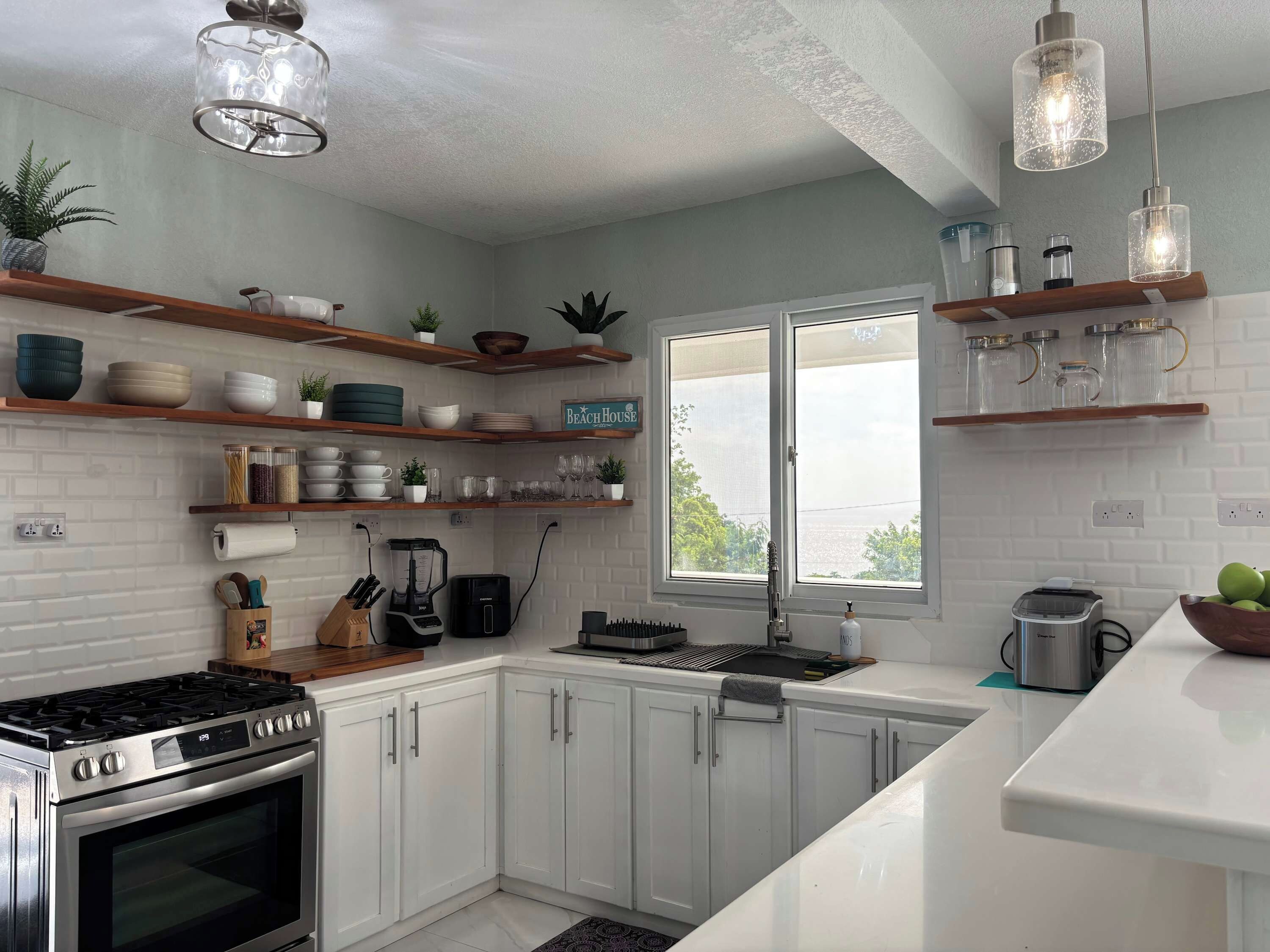 Una cucina moderna con mobili bianchi, forno integrato, macchina da caffè e una finestra con vista.