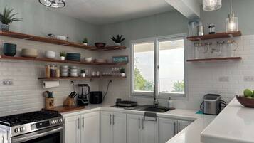 Una cucina moderna con mobili bianchi, forno integrato, macchina da caffè e una finestra con vista.