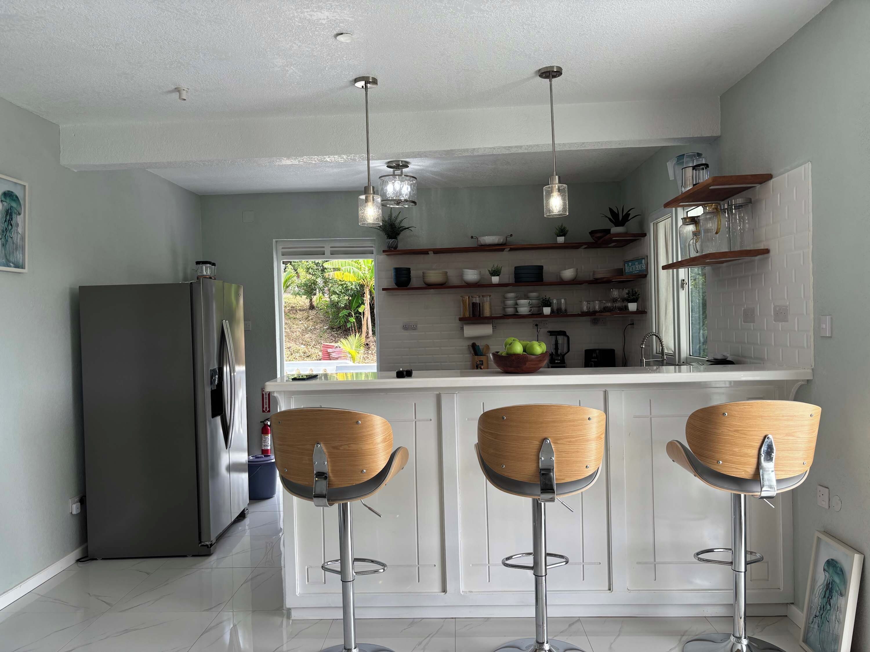 A modern kitchen with a central island, bar stools, and pendant lighting.