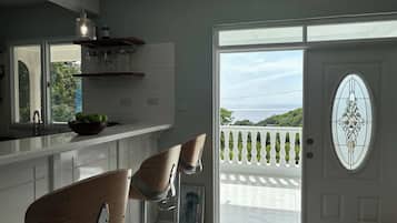 Una cucina moderna con un'ampia finestra, due sgabelli da bar e una porta decorativa vista mare.