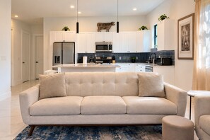 A modern living room with a beige sofa, a coffee table, and a rug.
