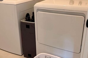 Una lavadora blanca con puerta frontal y un pequeño compartimento a la izquierda.