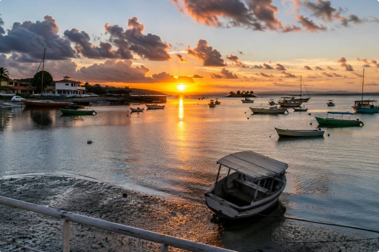 Escena costera con barcos amarrados en un puerto deportivo al atardecer.