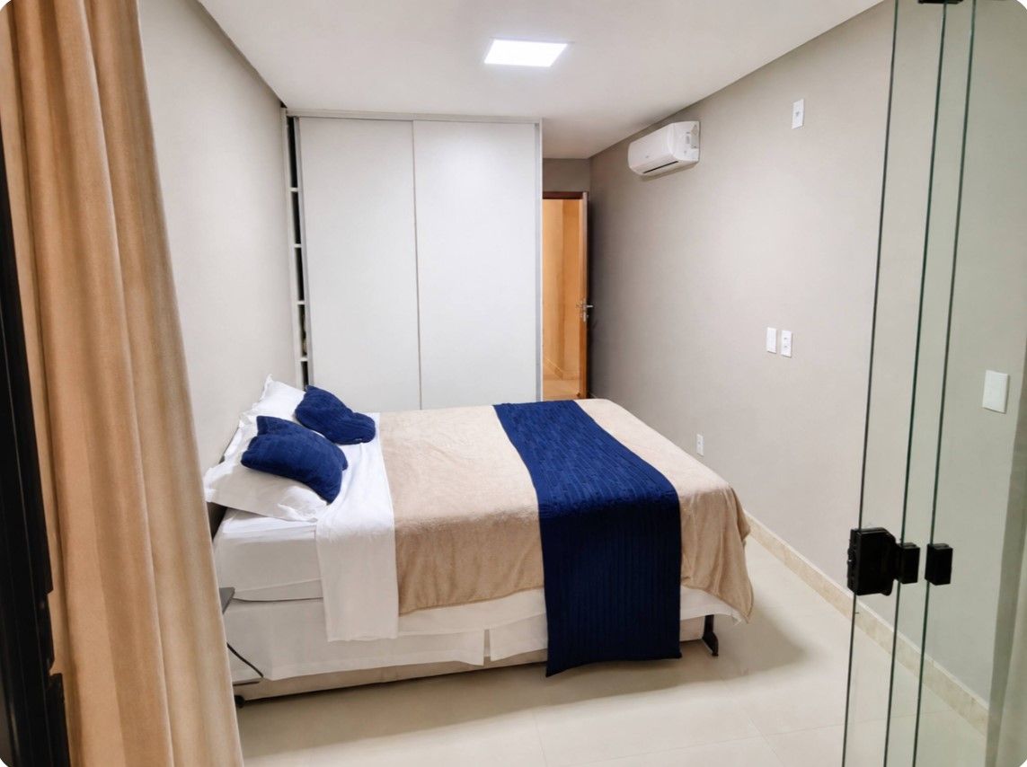 A bedroom with a bed, a wardrobe, and an air conditioning unit.