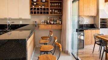 Een moderne keuken met een centraal eiland, houten kastjes en een wijnrek.