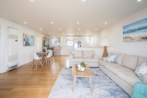 A modern living room with a sofa, coffee table, and dining area.