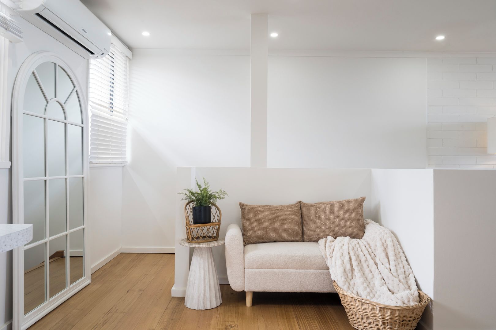 Een moderne kamer met een bank, een klein bijzettafeltje met een plant en een rieten mand.