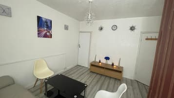 A modern living room with a sofa, a white chair, a black coffee table, and a wooden side table with candles.