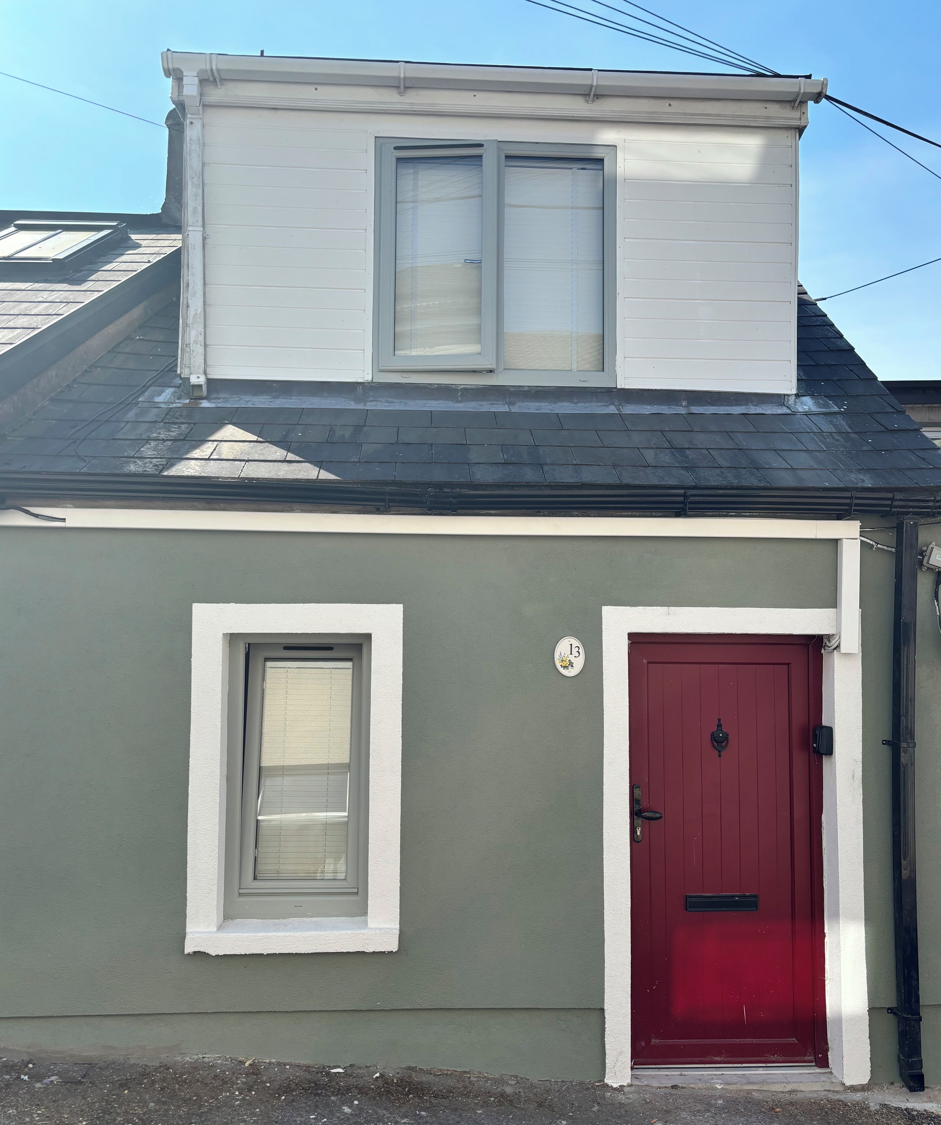 A two-story building with a red door and a window with blinds.