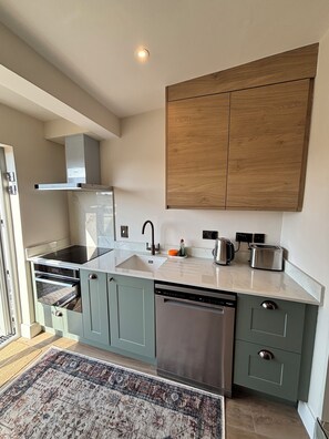 A modern kitchen with a built-in oven, a dishwasher, a sink, and a wooden cabinet above the countertop. - River View Newly Renovated Irish Townhouse in Cork City and near UCC (Cork)