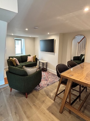 A modern living room with a green sofa, a wooden dining table, and a large mirror. - River View Newly Renovated Irish Townhouse in Cork City and near UCC (Cork)