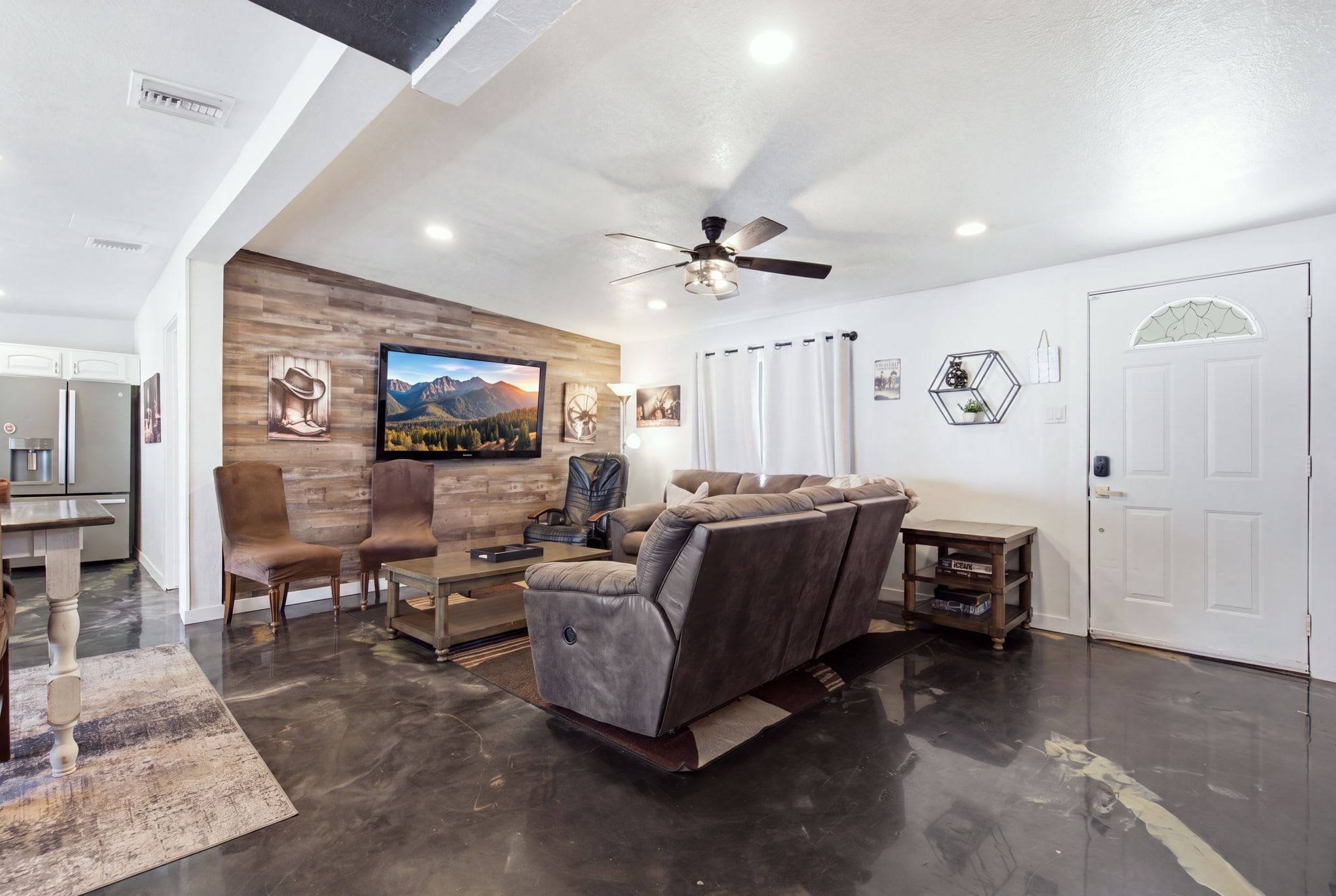 A modern living room with a flat-screen TV, leather recliner, and a dining area with a wooden table and chairs.