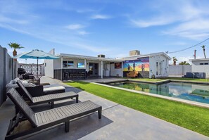 Eine moderne Terrassenanlage im Freien mit Pool, Liegestühlen und Barbereich.