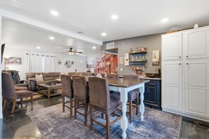 A dining area with a table and chairs, a kitchen with cabinets, and a ceiling fan. - Outlaw - Pool - Putting Green - Mins to Old Town (Scottsdale)