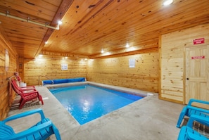 A wooden interior with a pool, red lounge chairs, and a fire safety sign. - Make Lasting Memories: Pool, Hot Tub, Games & MORE (Pigeon Forge)
