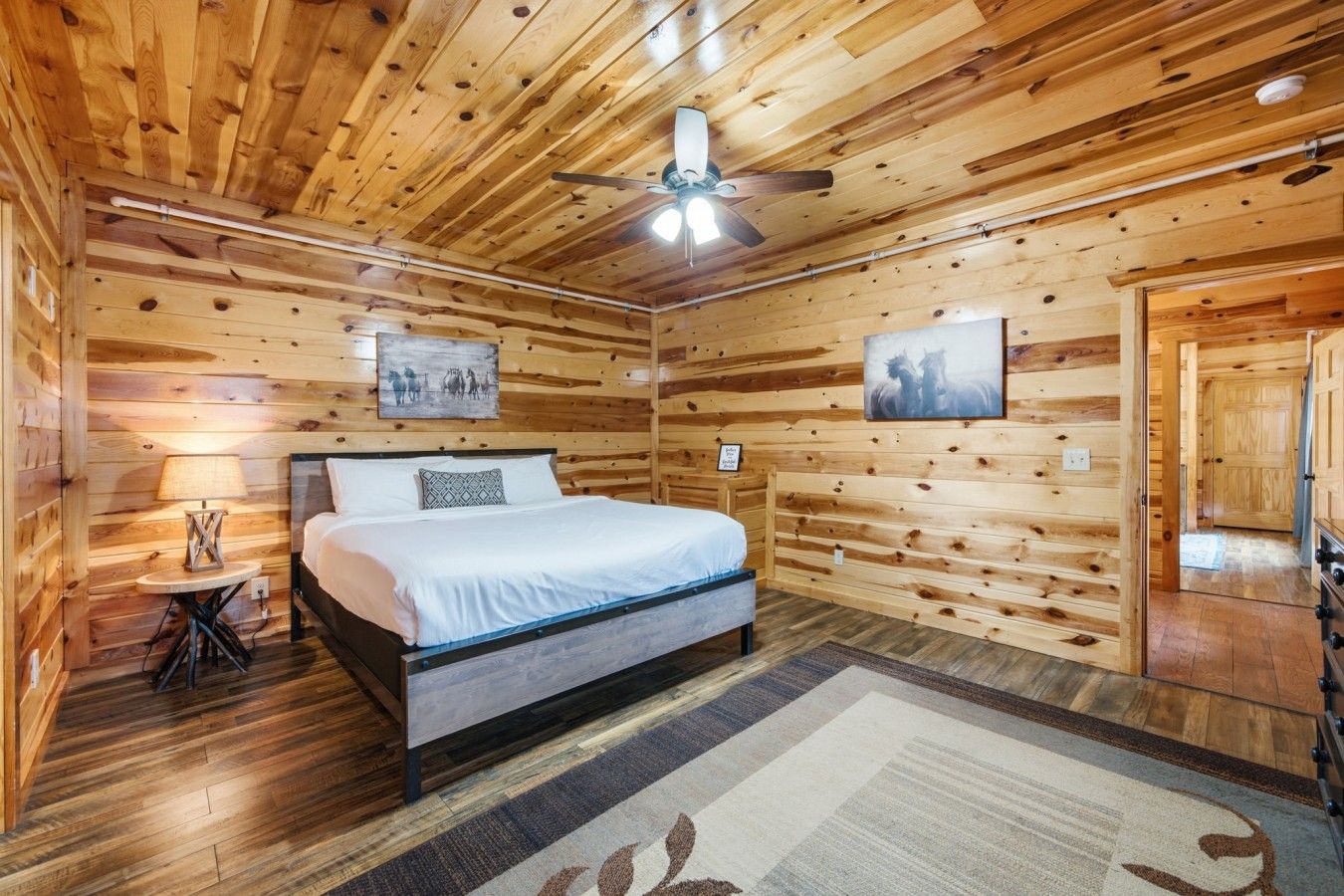 Une chambre dans une cabane en bois, avec un lit, un ventilateur de plafond et un tapis.