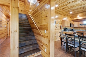 A wooden interior with a staircase leading to a dining area. - Make Lasting Memories: Pool, Hot Tub, Games & MORE (Pigeon Forge)