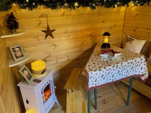 A cozy room with a wooden interior, a small table with a festive tablecloth, a lit lantern, and a star decoration on the wall.