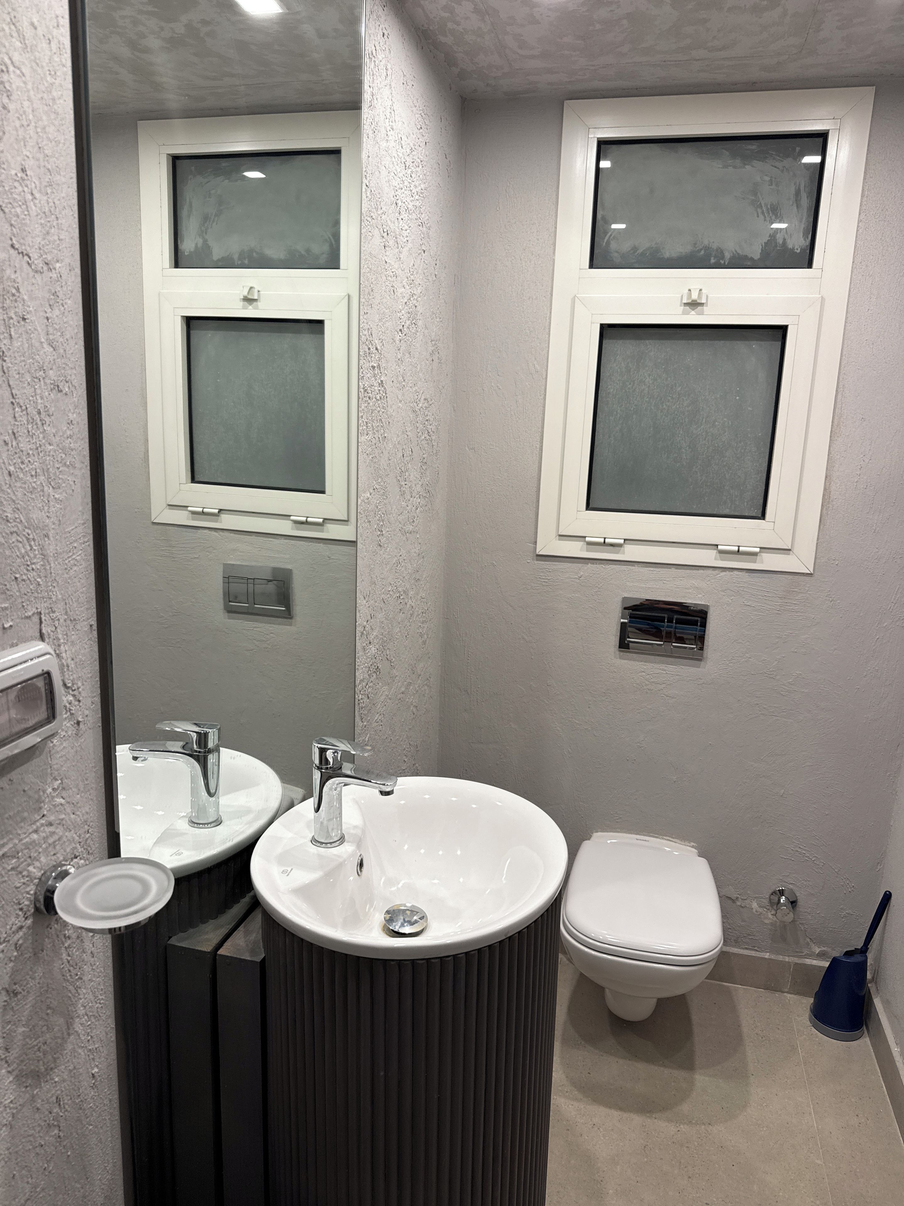 A bathroom with two sinks, a toilet, and a window.