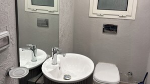 Een badkamer met twee wastafels, toilet en raam.