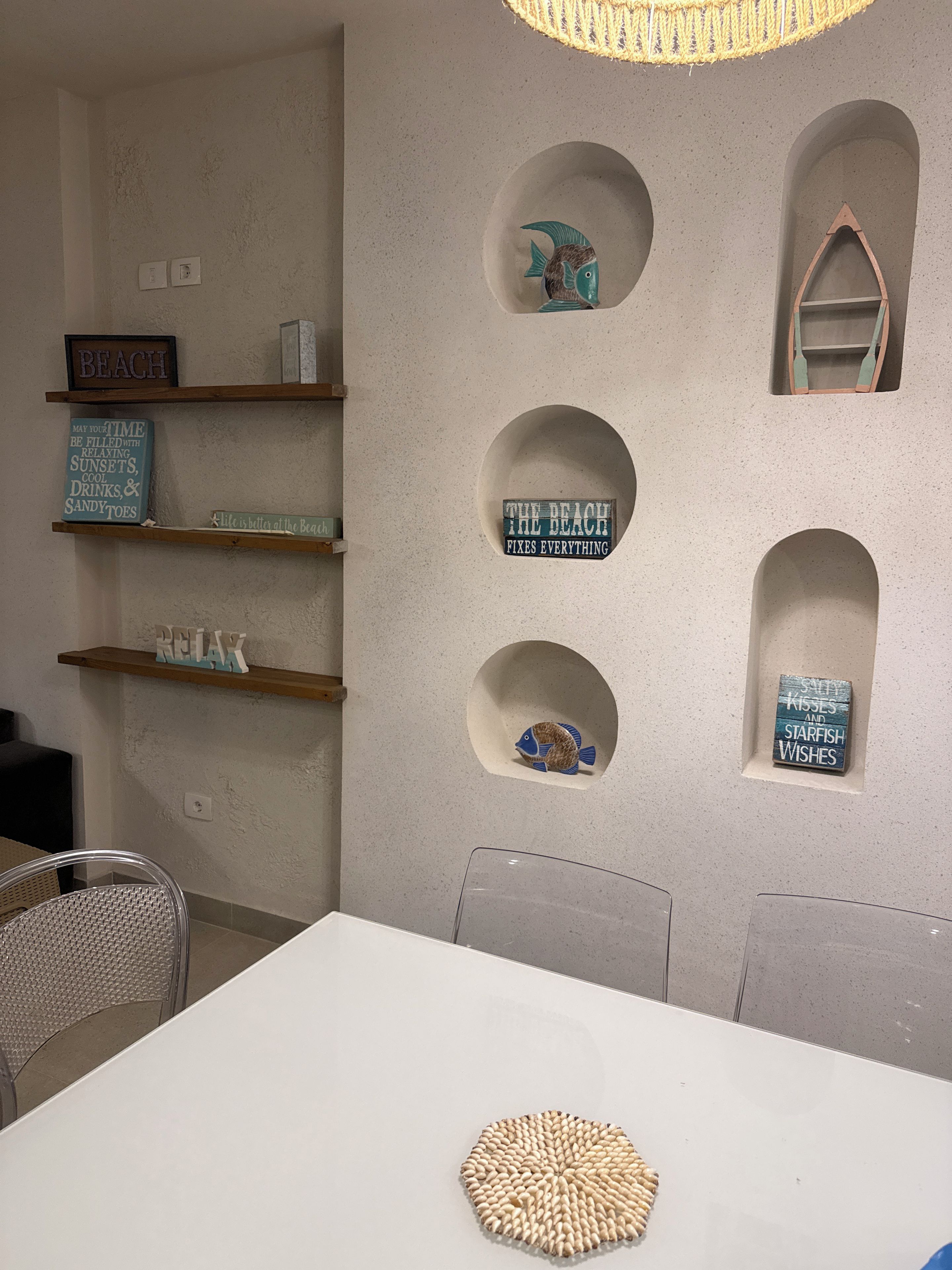 A room with a white table, chairs, and a wall with circular cutouts containing various items.