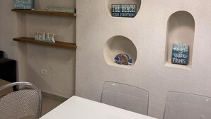 Een kamer met een witte tafel, stoelen en een wand met ronde uitsparingen waarin verschillende objecten staan.