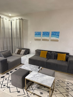 A living room with a sectional sofa, a coffee table, and a patterned rug. - Cozy 3-bedroom chalet in perfect white sand at Beit Al Bahr Sidi Hanesh (Marsa Matrouh Governorate)